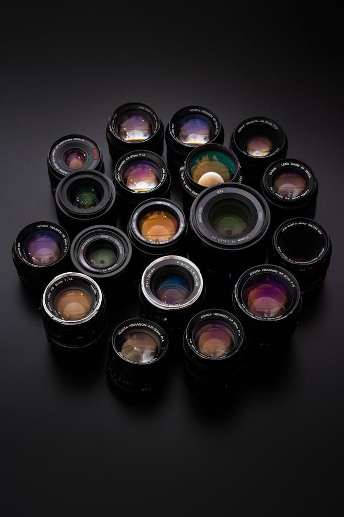 Diverse collection of camera lenses arranged on a sleek black surface.